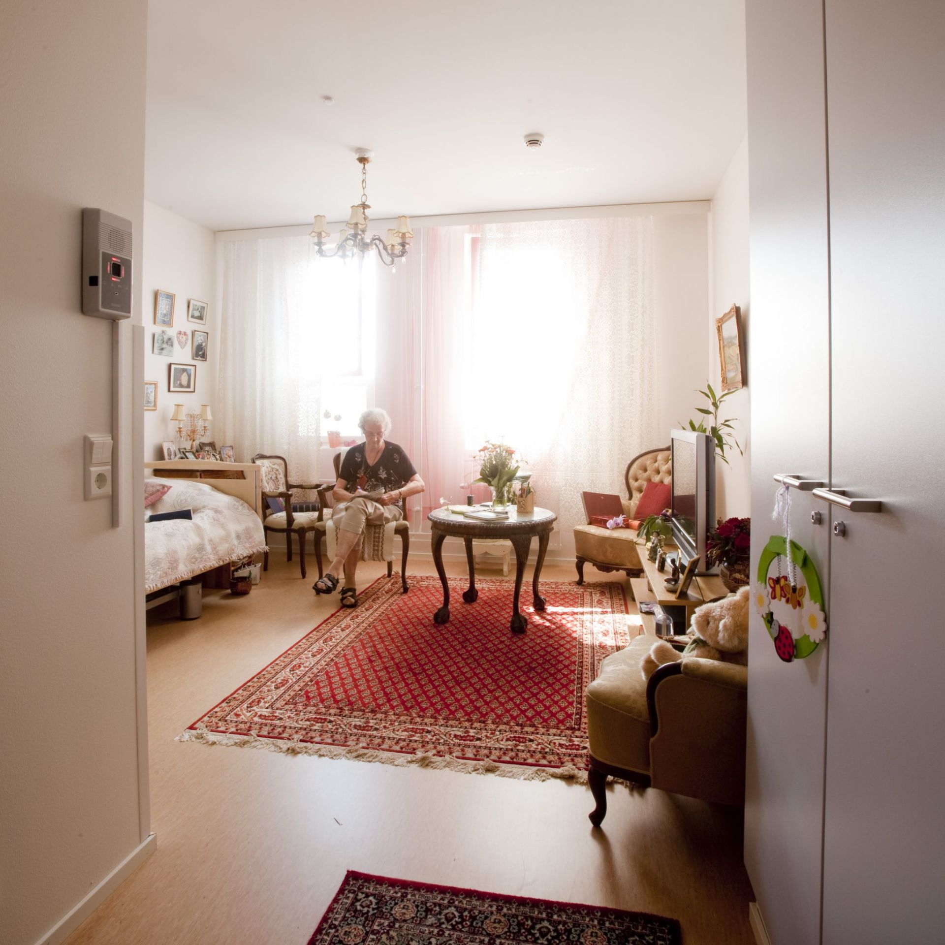 En aeldre person sitter vid ett bord i ett moeblerat rum